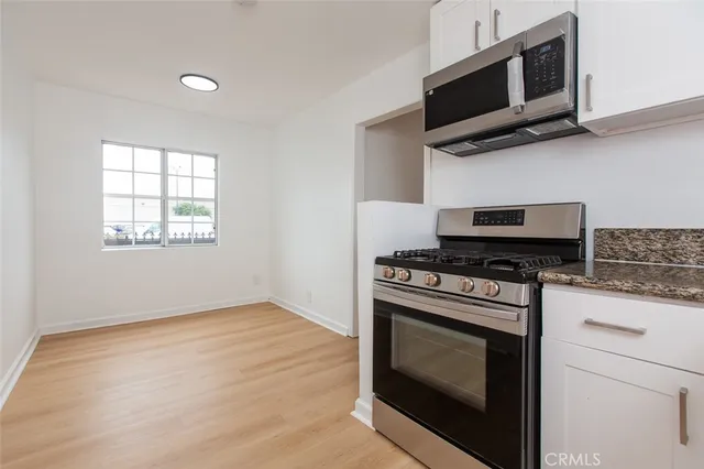 a kitchen with stainless steel appliances a stove a microwave cabinets and a window