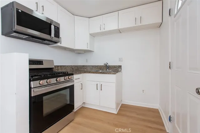 a kitchen with cabinets stainless steel appliances and a wooden floor