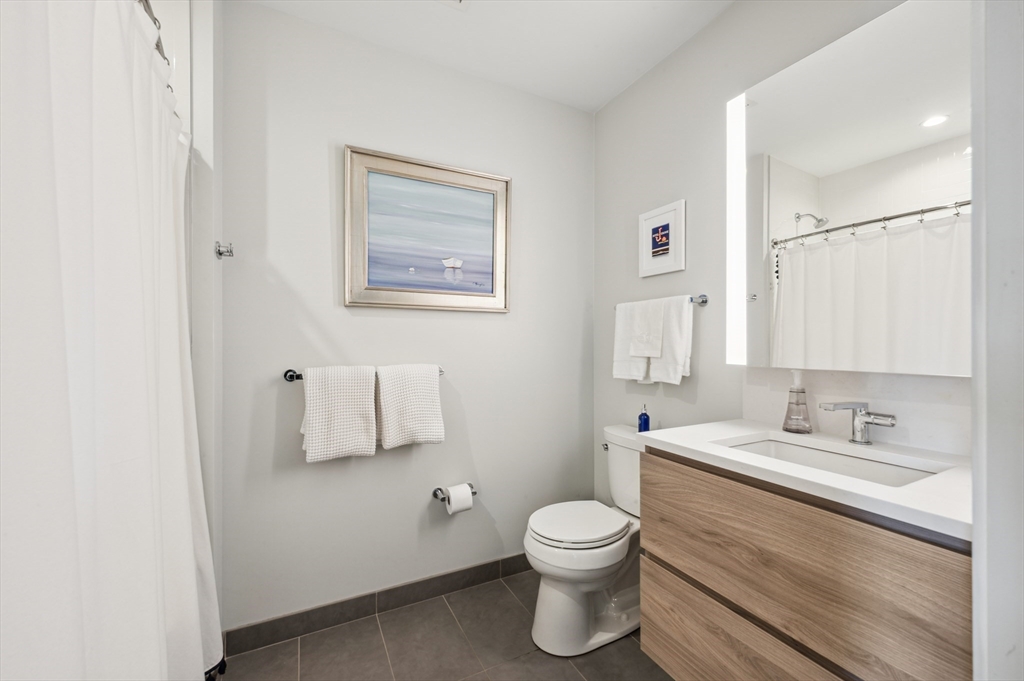 133 Seaport Boulevard, Unit 823 Boston, MA 02210 - Photo 20 of 31 a bathroom with a toilet sink vanity and mirror