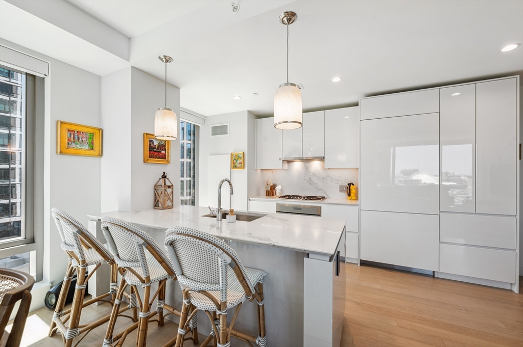 133 Seaport Boulevard, Unit 823 Boston, MA 02210 - Photo 5 of 31 a kitchen with granite countertop a table chairs stainless steel appliances and cabinets