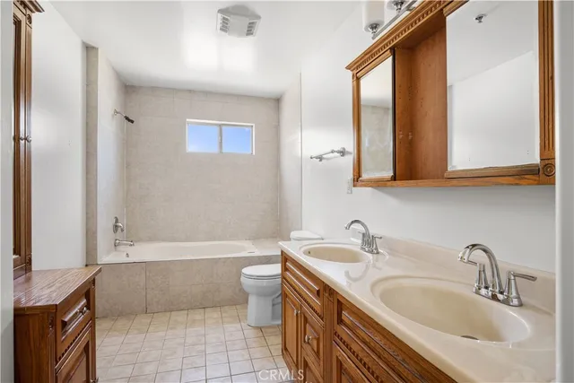 a bathroom with a granite countertop bathtub sink vanity mirror and toilet