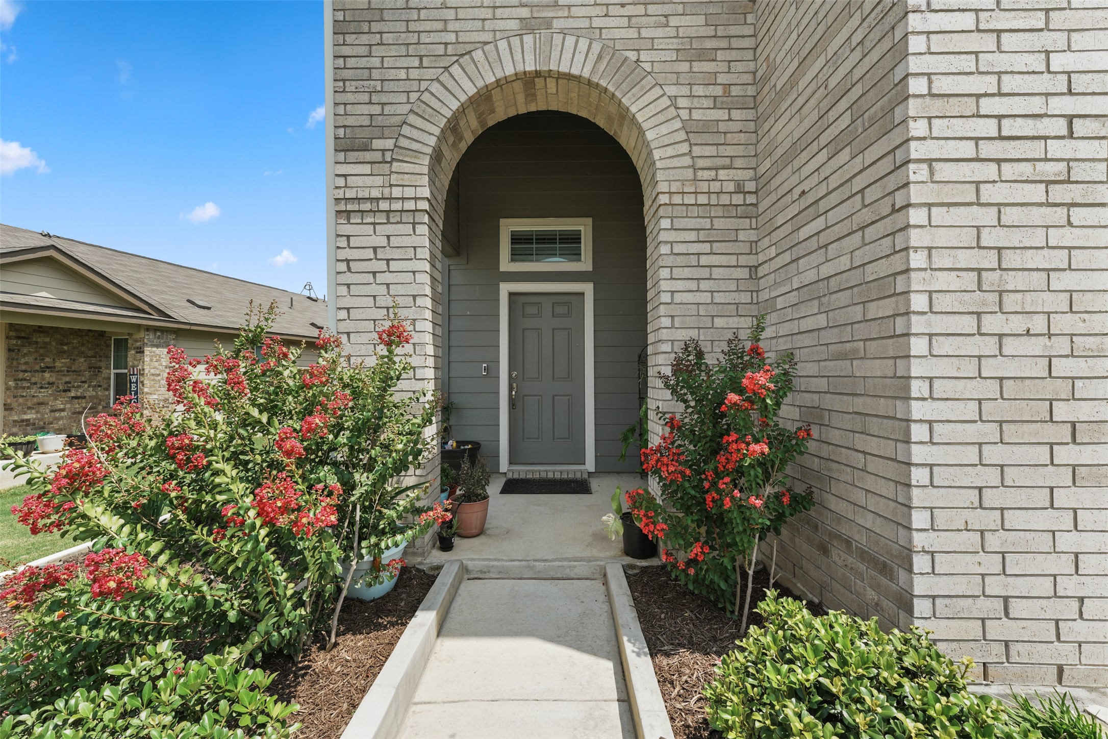 413 Perfect World Loop Jarrell, TX 76537 - Photo 6 of 39 An inviting arched entryway welcomes you into this charming home, framed by flourishing, colorful shrubs.