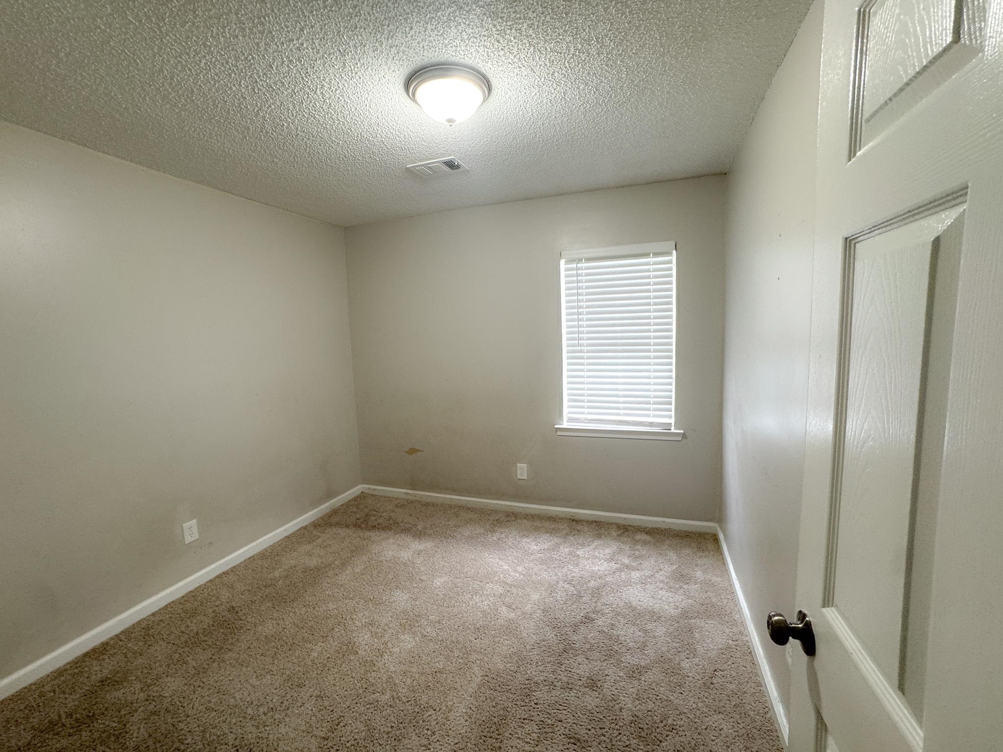 3592 Christine Road Memphis, TN 38118 - Photo 12 of 13 Carpeted room with a single window featuring white blinds, neutral wall paint, and a textured ceiling
