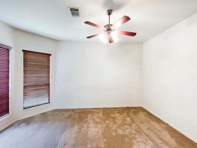 an empty room with wooden floor chandelier fan and windows