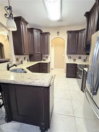 a kitchen with kitchen island granite countertop a sink a stove and a refrigerator