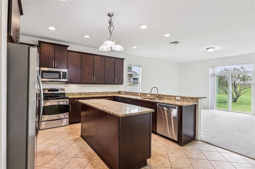1126 Maumee Street Orlando, FL 32828 - Photo 5 of 21 a kitchen with kitchen island granite countertop stainless steel appliances a sink stove and cabinets