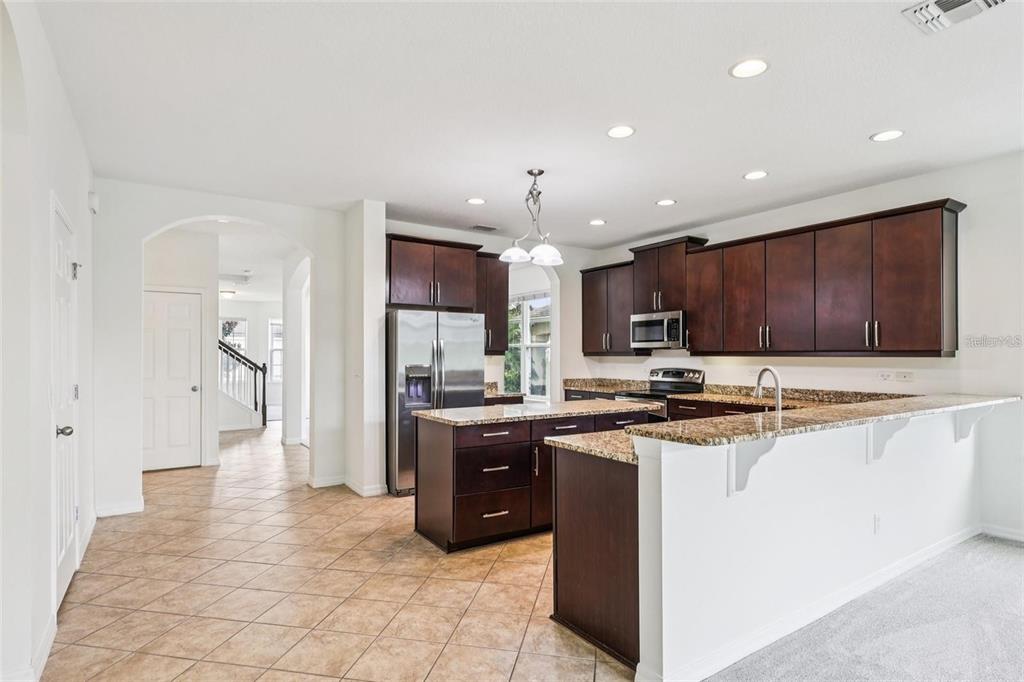 1126 Maumee Street Orlando, FL 32828 - Photo 6 of 21 a kitchen with stainless steel appliances granite countertop a stove top oven a sink and a refrigerator