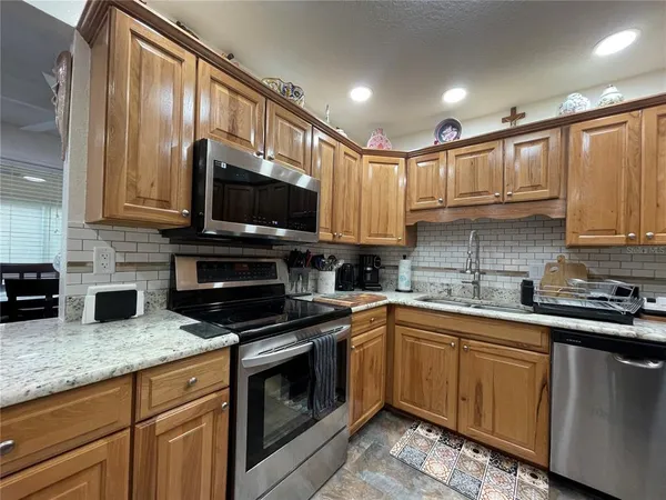a kitchen with stainless steel appliances granite countertop a sink a stove and cabinets