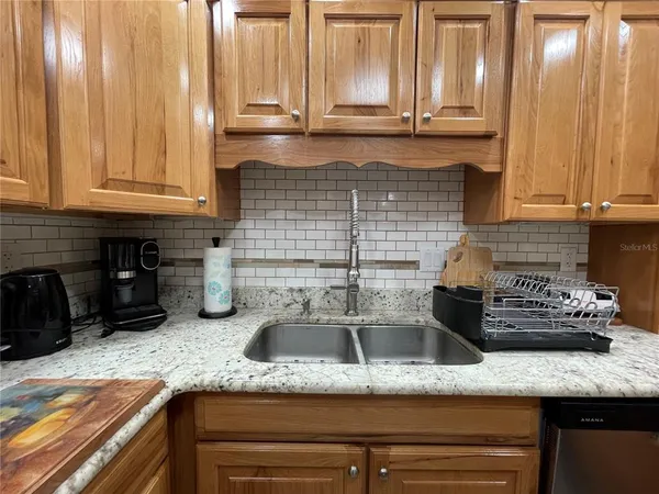 a kitchen with granite countertop stainless steel appliances a refrigerator a sink a stove top oven and cabinets