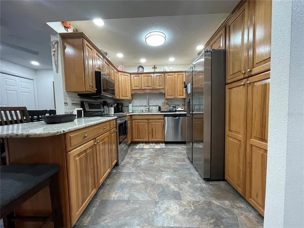 a kitchen with stainless steel appliances granite countertop a sink a stove top oven a refrigerator and cabinets