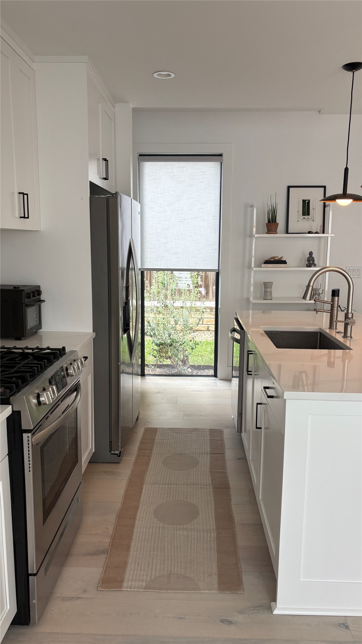 1816 Adina Street, Unit 2 Austin, TX 78721 - Photo 7 of 25 Contemporary kitchen featuring white cabinetry, stainless steel appliances, light-toned wood-finish flooring, and a large window providing outdoor exposure