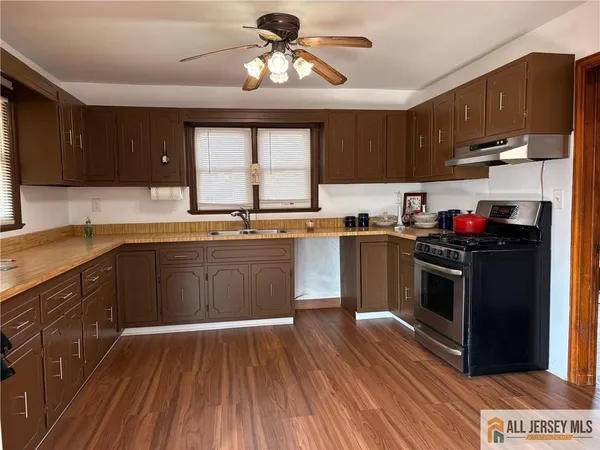 a kitchen with stainless steel appliances granite countertop wooden cabinets a sink a stove a refrigerator and island