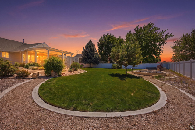 776 Flint Street Layton, UT 84041 - Photo 41 of 41 Landscaped backyard featuring a circular lawn area, gravel pathways, and a built-in fire pit