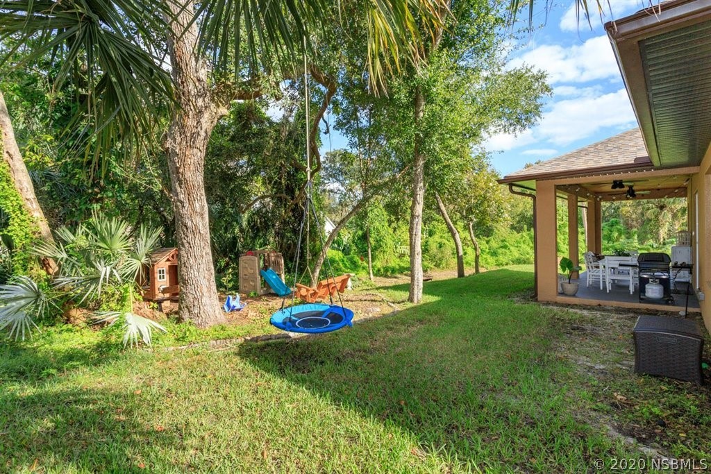 141 Poinciana Road Edgewater, FL 32141 - Photo 20 of 26 a view of a backyard with table and chairs potted plants and large tree