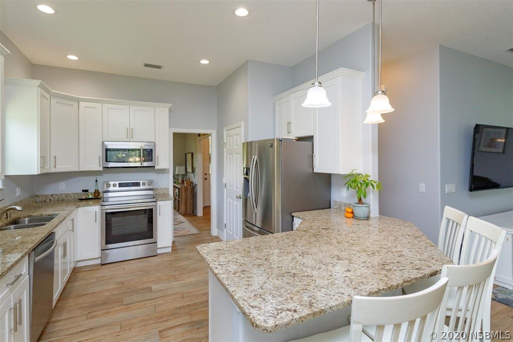 141 Poinciana Road Edgewater, FL 32141 - Photo 3 of 26 a kitchen with stainless steel appliances granite countertop a kitchen island a stove a microwave a refrigerator a sink and a refrigerator