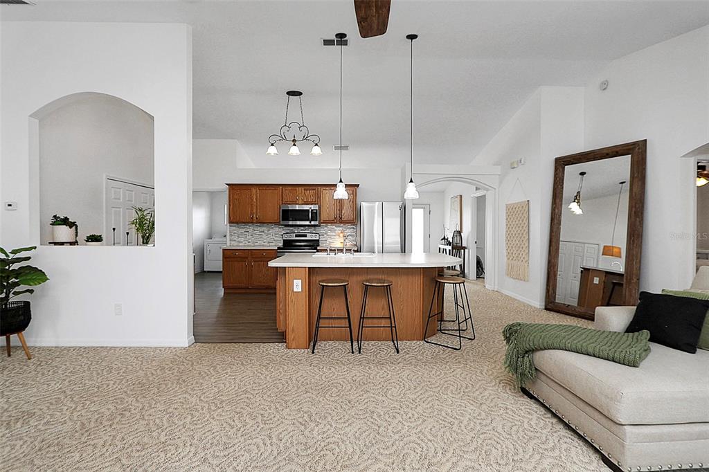 10648 Southwest 38th Avenue Ocala, FL 34476 - Photo 22 of 52 a living room with furniture a chandelier and kitchen view