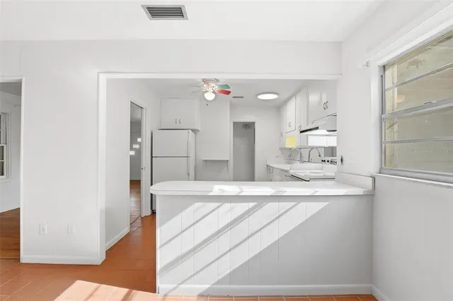 a kitchen with refrigerator a stove and white cabinets