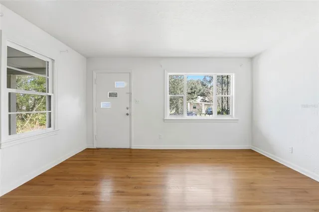 a view of an empty room with wooden floor and a window