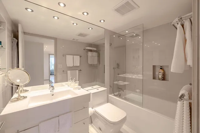 a bathroom with a sink a toilet a mirror and shower