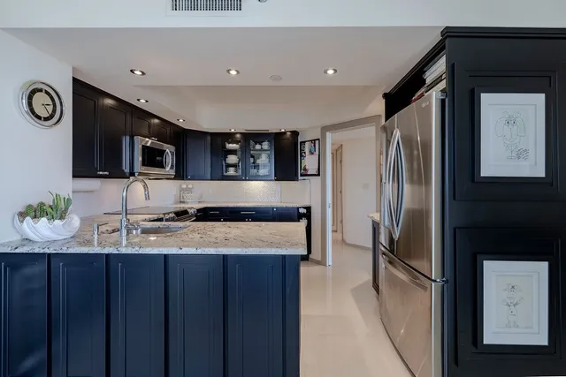 a kitchen with stainless steel appliances granite countertop a refrigerator a stove top oven and a sink