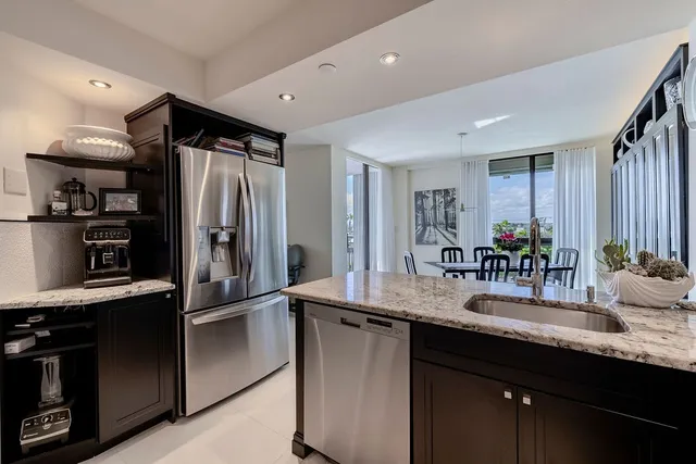 a kitchen with stainless steel appliances granite countertop a sink and a refrigerator