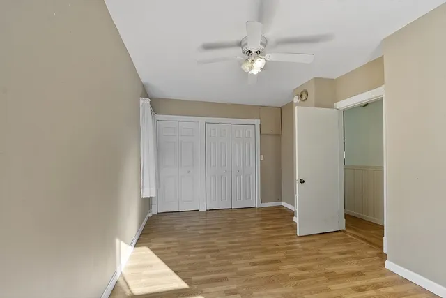 a view of empty room with wooden floor and fan