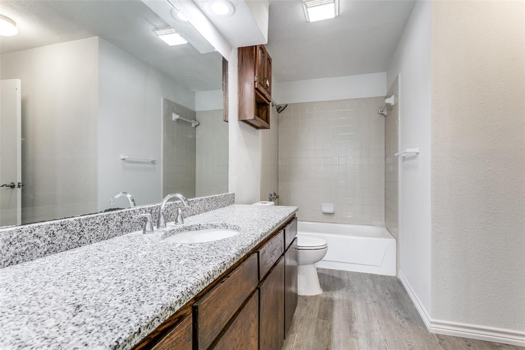 2121 Stone Moss Lane Grapevine, TX 76051 - Photo 9 of 12 Full bath featuring granite vanity, wood cabinets, bath/shower combination that leads into downstairs primary bedroom