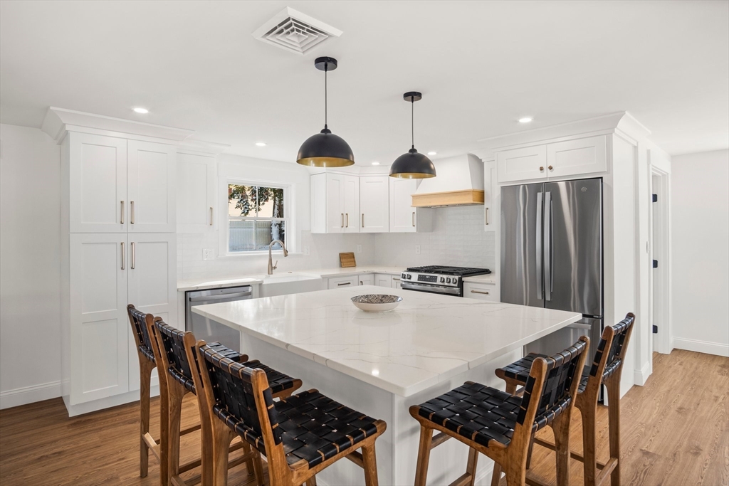 4 Jethro Street Maynard, MA 01754 - Photo 6 of 29 a kitchen with stainless steel appliances a dining table chairs and white cabinets
