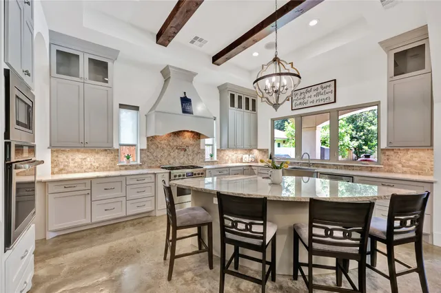 a kitchen with kitchen island granite countertop a table chairs sink and cabinets