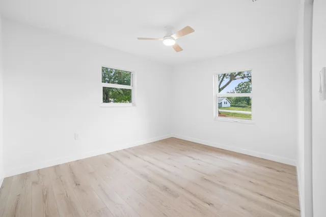 an empty room with wooden floor and window