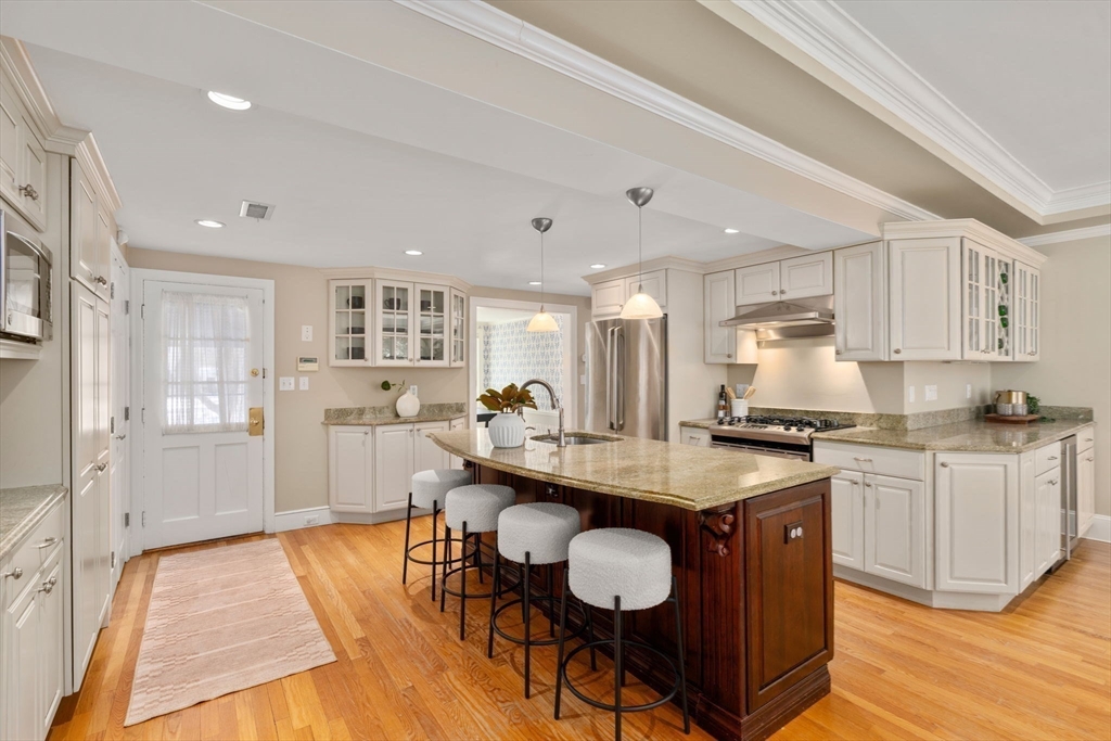 6 Boulder Brook Road Wellesley, MA 02481 - Photo 5 of 34 a kitchen with stainless steel appliances granite countertop a stove top oven a sink dishwasher a dining table and chairs with wooden floor