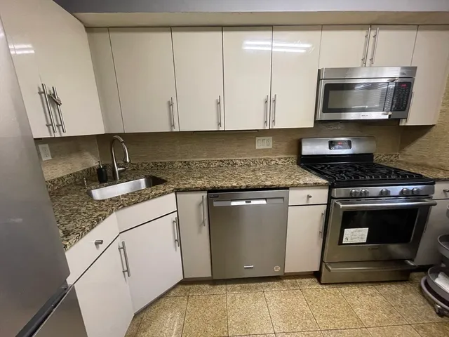 a kitchen with stainless steel appliances granite countertop a sink stove and microwave