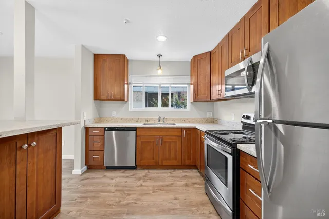 a kitchen with stainless steel appliances granite countertop a refrigerator a sink dishwasher a stove and white cabinets with wooden floor