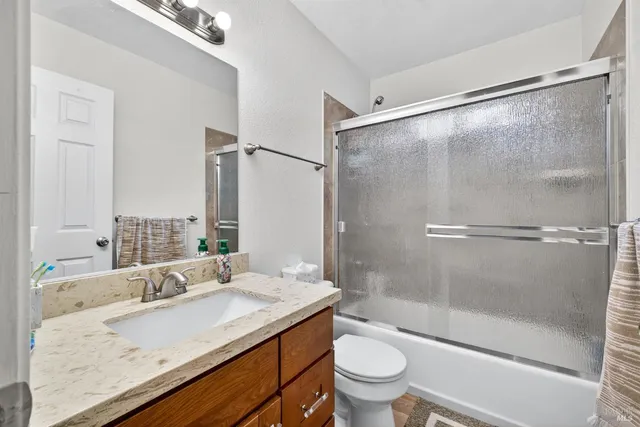 a bathroom with a granite countertop sink toilet and shower