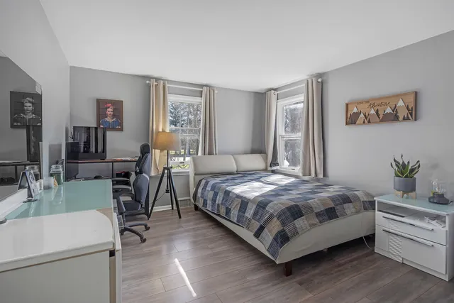 a bedroom with a bed wooden floor and window