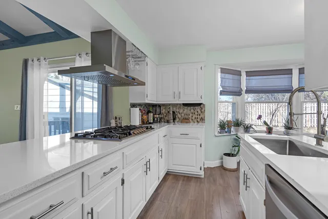 a kitchen with a sink a stove cabinets and wooden floor