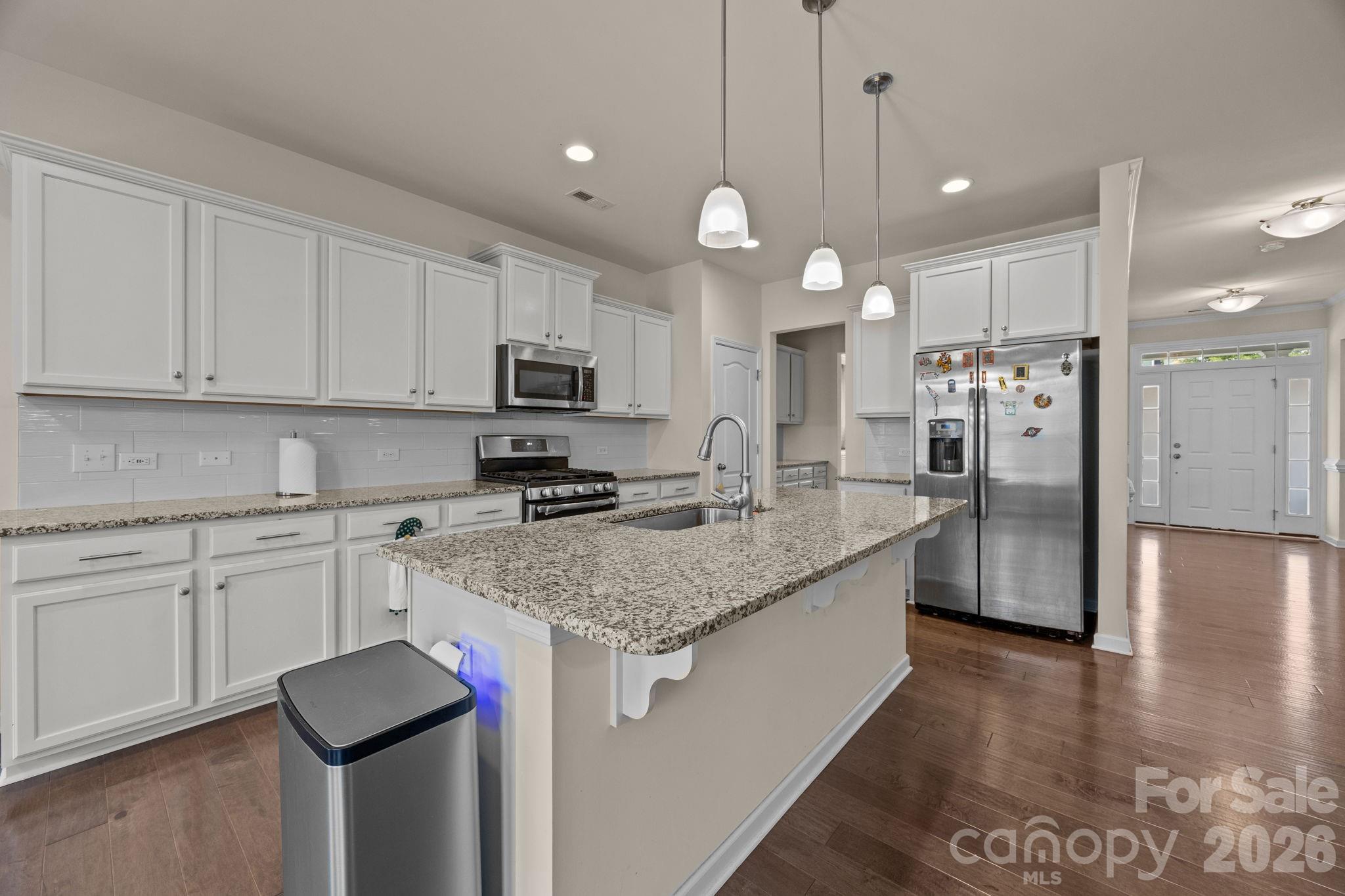 4028 Whittier Lane Tega Cay, SC 29708 - Photo 12 of 46 a kitchen with stainless steel appliances granite countertop a sink a stove a refrigerator and island with wooden floor