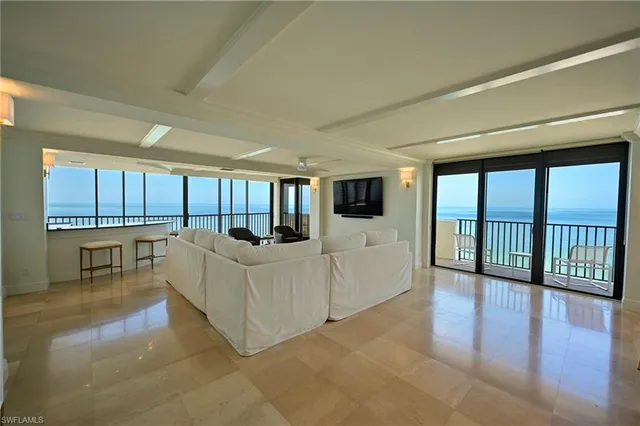 a living room with furniture large windows and wooden floor