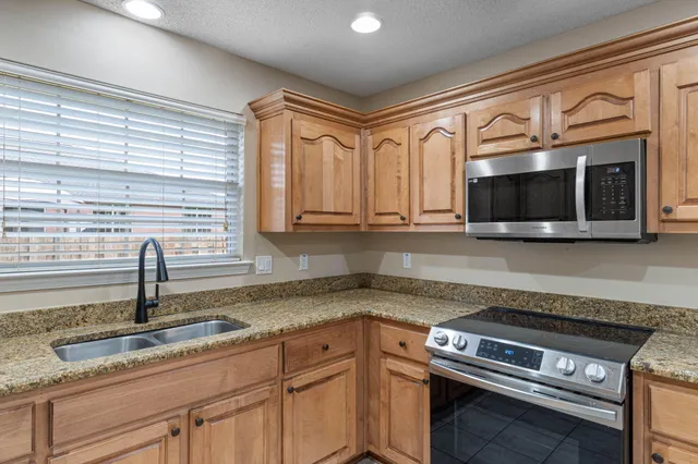 a kitchen with granite countertop a sink stainless steel appliances and cabinets