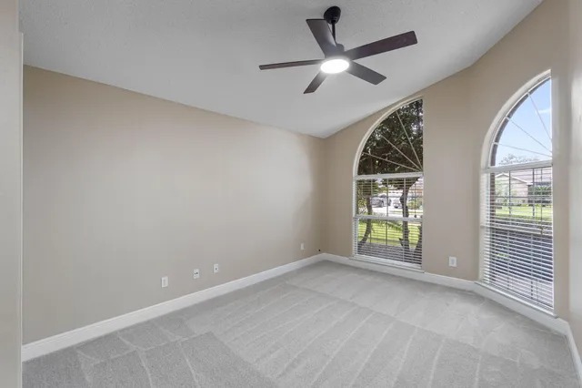 an empty room with windows and ceiling fan