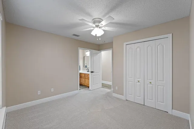 an empty room with closet and a ceiling fan