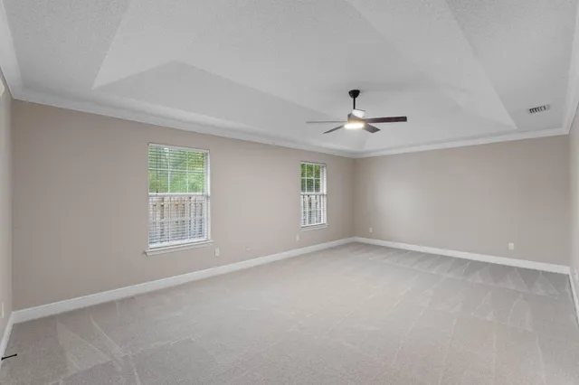 an empty room with windows and ceiling fan