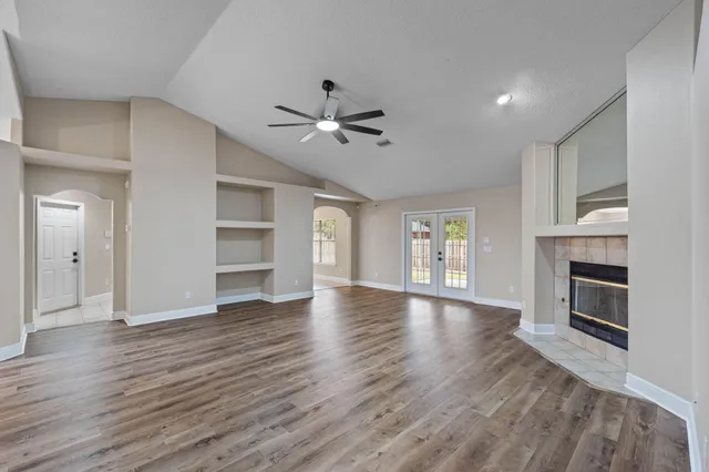 an empty room with wooden floor fireplace and windows