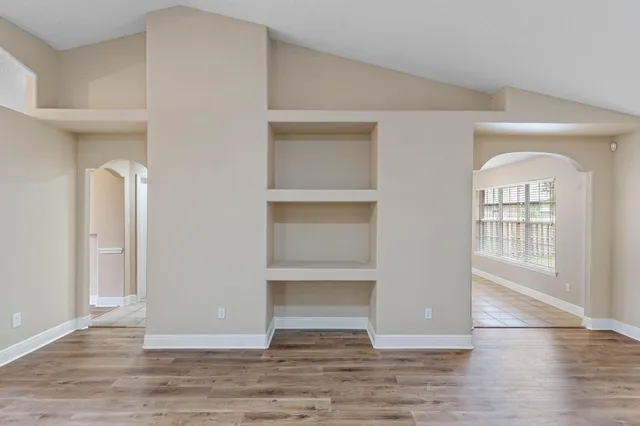 an empty room with wooden floor and windows