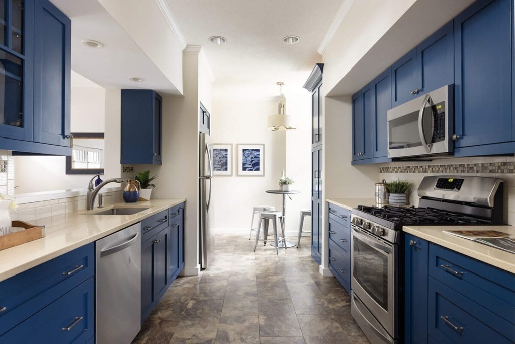 a kitchen with stainless steel appliances granite countertop a stove top oven a sink dishwasher a refrigerator and a microwave