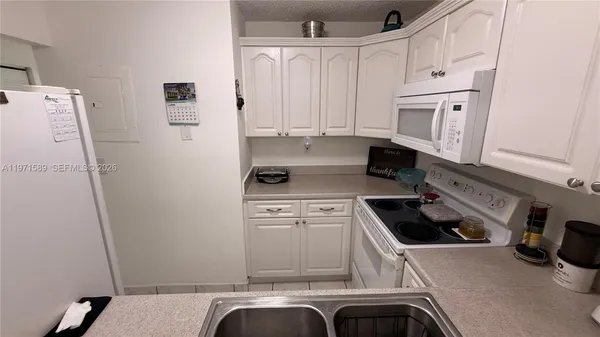 a kitchen with white cabinets and white appliances