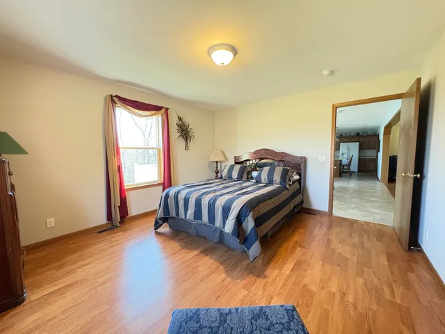 a spacious bedroom with a bed and wooden floor