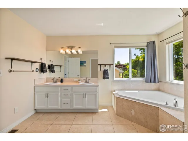 a bathroom with a sink a large mirror and a bathtub next to a window