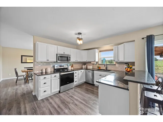 a kitchen with cabinets wooden floor and stainless steel appliances