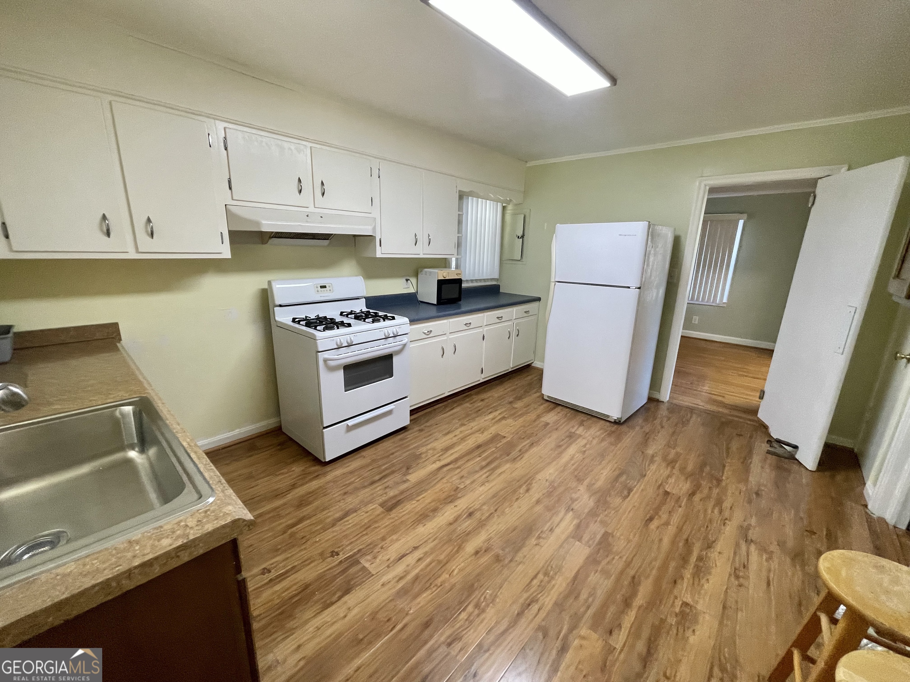 220 Airport Road Griffin, GA 30223 - Photo 8 of 23 a kitchen with a sink a refrigerator a stove and white cabinets
